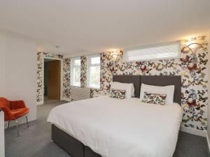 a bedroom with a large white bed with floral wallpaper at BRANTLEA Detached 4 Bed Home, Hot Tub, Lake View, Parking, Pet Friendly in Bowness-on-Windermere