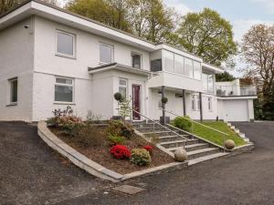 a white house with a red door and some flowers at BRANTLEA Detached 4 Bed Home, Hot Tub, Lake View, Parking, Pet Friendly in Bowness-on-Windermere