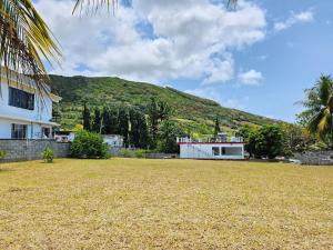 a house with a hill in the background with a yard at Cocotiers in Beau Champ