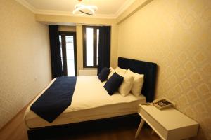 1 dormitorio con 1 cama con sábanas y almohadas blancas en Asmali Hotel, en Estambul