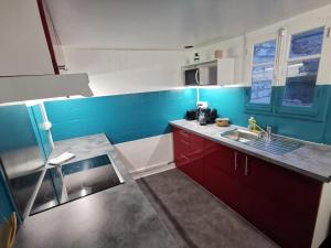 una cocina con armarios rojos y una pared azul en Bloody Mary, en Sens