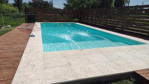 a large swimming pool with a wooden fence at Complejo cabañas el paraje in Ranchos