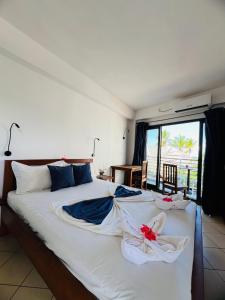 a bedroom with a large white bed with towels on it at Hôtel Grand Bay in Nosy Be
