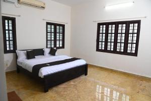 1 dormitorio con 1 cama con paredes y ventanas blancas en Royal Experiences Pearl House 6 Bed Room Villa with Private Pool, Panayur, en Chennai