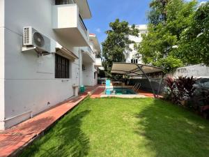 un patio trasero de una casa con césped verde en Royal Experiences Pearl House 6 Bed Room Villa with Private Pool, Panayur, en Chennai