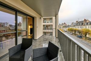 a balcony with two chairs and a view of a city at Le Manou, Appartement neuf avec terrasse, parking sous-terrain & ascenseur by PRIMO C0NCIERGERIE in Nevers