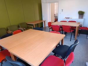 a classroom with wooden tables and red chairs at Gästehaus Maria Rast in Suderburg