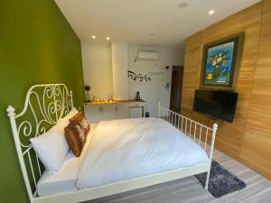 a bedroom with a white bed with a green wall at 忘憂天空民宿 in T'an-nan