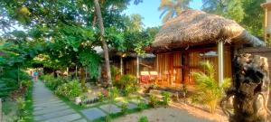 a house with a thatched roof and a pathway at The Coast Beach Resort in Agonda