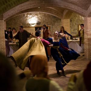 a group of people dressed in medieval costumes dancing at Castello di Baccaresca in Branca