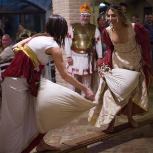 dos mujeres con ropa medieval bailando delante de un grupo de personas en Castello di Baccaresca, en Branca
