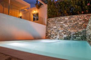 - une piscine avec un mur en pierre et une baignoire dans l'établissement Aeolos Hotel & Villas - Pelion, à Chorefto