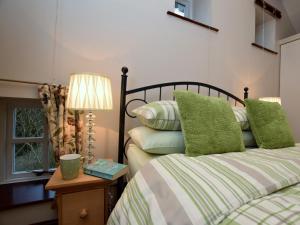 een slaapkamer met een bed met groene kussens en een lamp bij 1 Bed in Ashford in the Water PK547 in Ashford