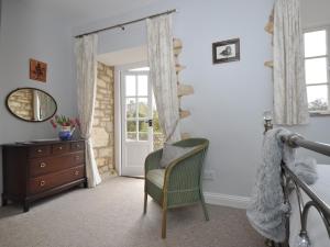 a bedroom with a chair and a dresser and a mirror at 1 Bed in Bourton-on-the-Water 44960 in Withington