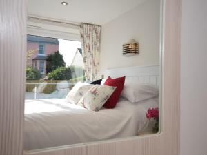um reflexo de espelho de uma cama com almofadas vermelhas e brancas em 2 Bed in Westward Ho 45753 em Northam