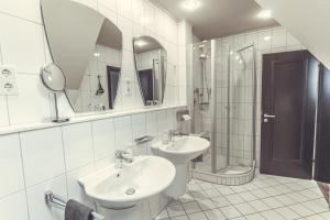 a bathroom with two sinks and a shower and a mirror at Hotel- Restaurant Einklang in Mettingen