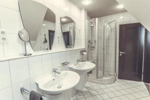 y baño con 2 lavabos, ducha y espejo. en Hotel- Restaurant Einklang en Mettingen