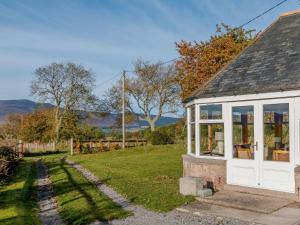 a small cottage with a white door and windows at 3 Bed in The Cairngorms 53150 in Dinnet