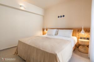 a bedroom with a large bed with white sheets at House Marigo Suites in Koskinou