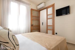 a bedroom with a bed and a flat screen tv at House Marigo Suites in Koskinou