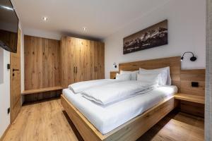 a bedroom with a large white bed with wooden walls at Waldnest in Kitzbühel