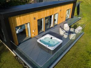 ein Haus mit einem Whirlpool auf einer Terrasse in der Unterkunft Birches Lodge with Hot Tub in Dundonnell