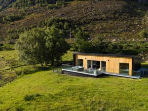 una casa en una colina con un campo verde en Birches Lodge with Hot Tub, en Dundonnell