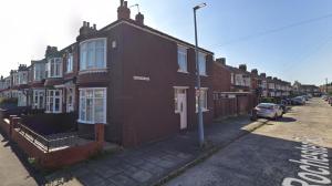a row of brick houses on a street with a car at Rochester House in Middlesbrough