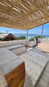 um pátio exterior com um telhado de madeira e uma mesa em Shore Thing Gili Air Beachfront Apartment em Gili Air