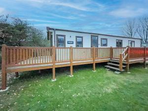 a mobile home with two benches and a fence at Beautiful 6 Berth Caravan At Caldecott Hall Country Park, Norfolk Ref 91150c in Great Yarmouth