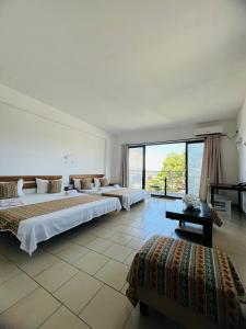 a bedroom with two beds and a large window at Hôtel Ambatoloaka in Nosy Be