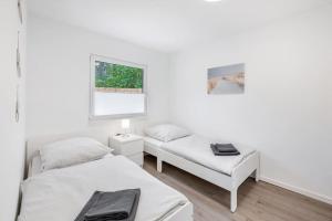 um quarto branco com 2 camas e uma janela em Ferienhaus Dünenwald em Dierhagen
