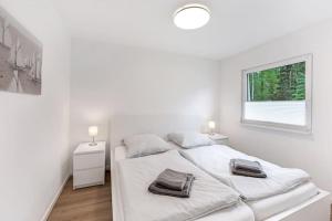 ein weißes Schlafzimmer mit 2 Betten und einem Fenster in der Unterkunft Ferienhaus Dünenwald in Dierhagen