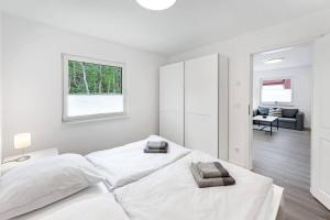 オストゼーバート・ディアーハーゲンにあるFerienhaus Dünenwaldの白いベッドルーム(ベッド2台付)、リビングルームが備わります。