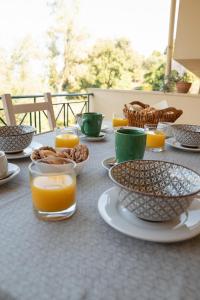 una mesa con platos de comida y vasos de zumo de naranja en Solari Hill Maisonette two private parking, en Corfú