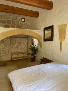 a bedroom with a white bed and a stone wall at Sansun Community House in Xewkija