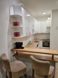 eine Küche mit weißen Schränken und einer Theke mit 2 Stühlen in der Unterkunft Apartman Teo Banja Luka in Banja Luka