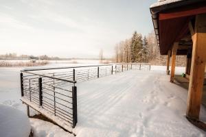 a deck covered in snow next to a building at Brīvdienu māja "Saules Avoti" in Talsi