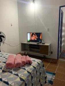Schlafzimmer mit einem Bett und einem TV auf einem Schreibtisch in der Unterkunft Céu azul in Vera Cruz de Itaparica
