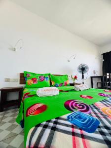 a bedroom with a green bed with colorful sheets and pillows at Hôtel Ambatoloaka in Nosy Be