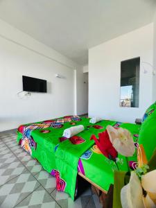 una camera con letto e piumone verde di Hôtel Ambatoloaka a Nosy Be