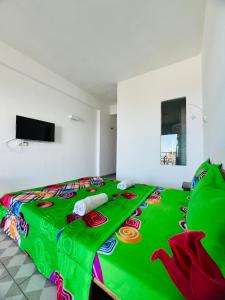 a bed with a green blanket on top of it at Hôtel Ambatoloaka in Nosy Be