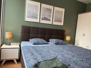 Schlafzimmer mit einem Bett mit blauer Decke und Bildern in der Unterkunft Apartment Mischa in Innsbruck