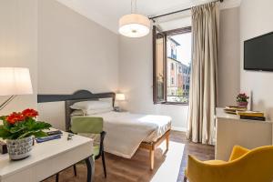 una camera d'albergo con letto, scrivania e finestra di HOTEL DELLE CIVETTE a Roma