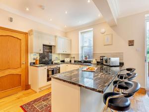 a kitchen with white cabinets and a counter with bar stools at 2 Bed in Alnwick CN218 in Alnwick