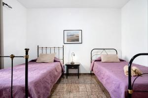 two beds in a room with purple sheets at Casa la solapa in Pájara
