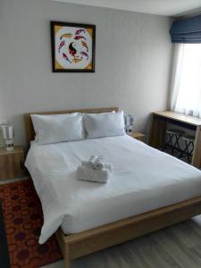 ein Bett mit weißer Bettwäsche und zwei Handtüchern darauf in der Unterkunft The Beach Residence by EHM in Nai Yang Beach