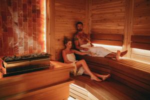 a man and a woman sitting in a sauna at Grund Resort Golf and Ski in Mladé Buky