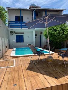 a blue umbrella and two chairs and a swimming pool at Céu azul in Vera Cruz de Itaparica