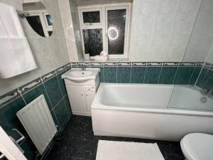 a bathroom with a tub and a toilet and a sink at Modern with Stylish Terrace - Your London Oasis! in London